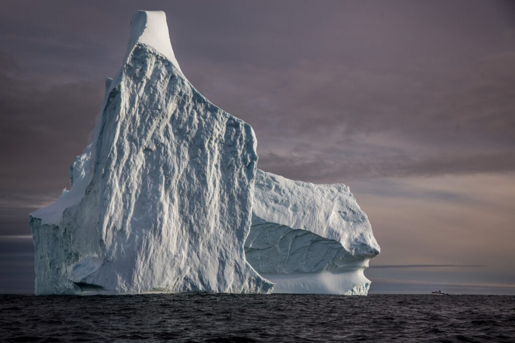 A huge iceberg and a tiny boat near Tasiilaq in East Greenland