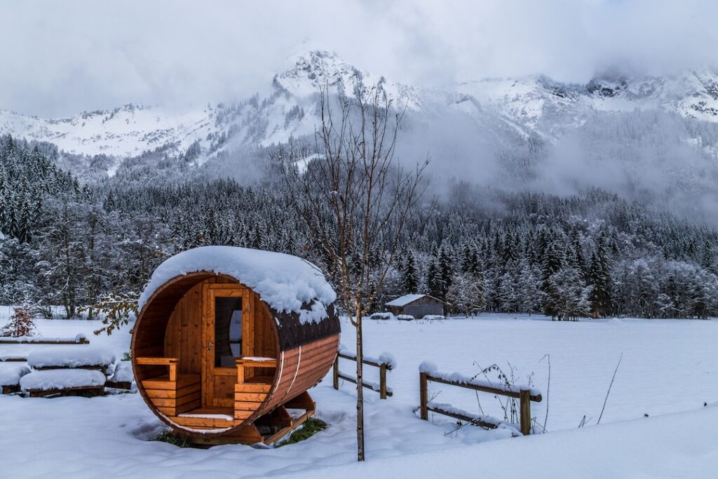 Sauna finlandesa em formato de barril em meio a uma paisagem nevada na Finlândia.