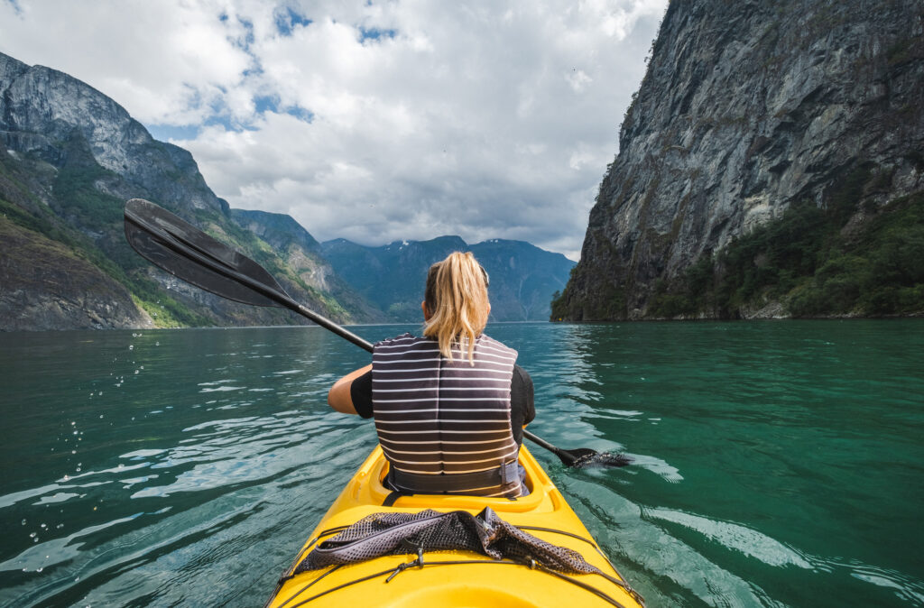 Woman kayaking in fjord in Norway.