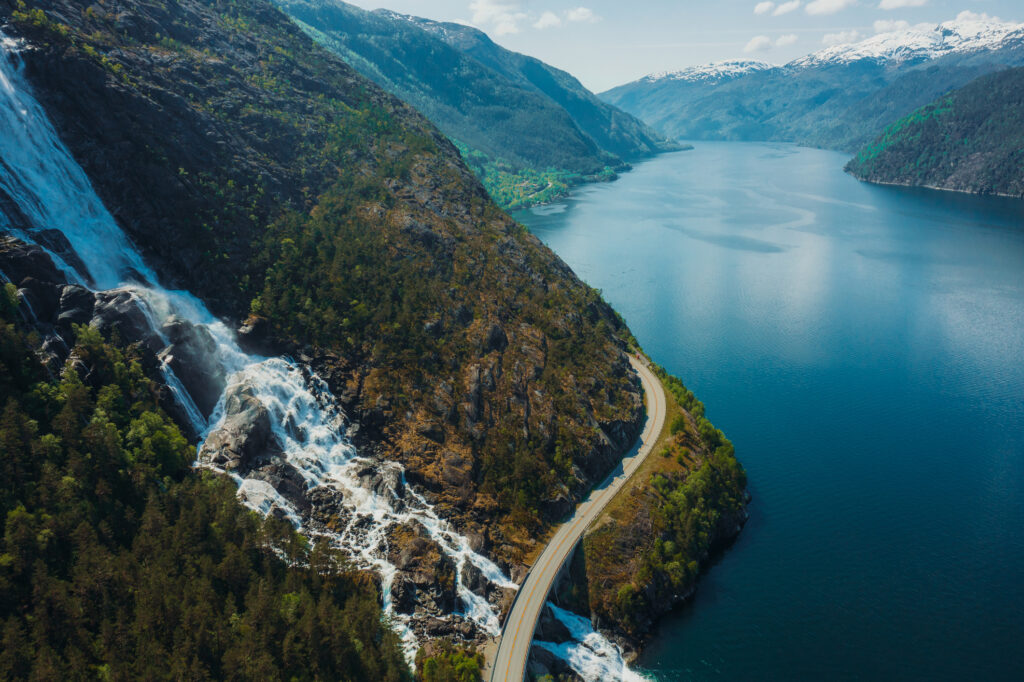 Drone high-angle photo of the curve road above the beautiful Langfoss waterfall with view of beautiful fjord in South Norway