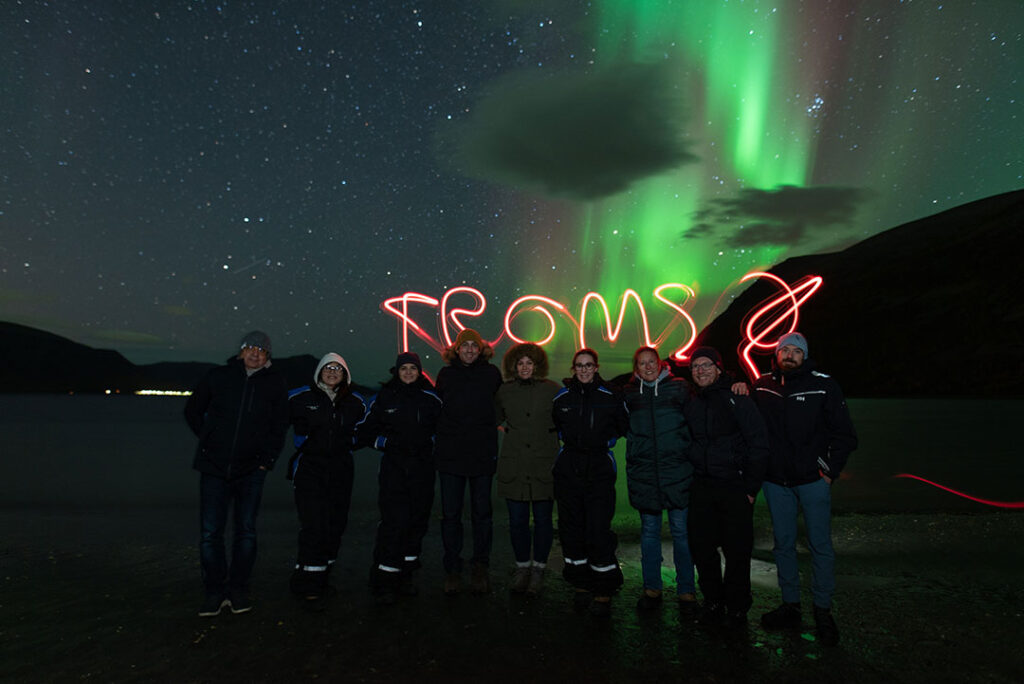 Grupo de pessoas diante da Aurora Boreal em Tromso, na Noruega