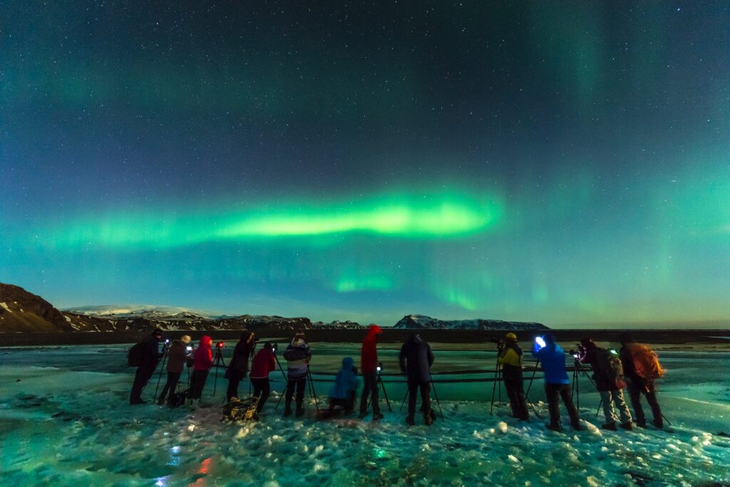 Grupo de pessoas se prepara para fotografar a Aurora Boreal durante uma caçada