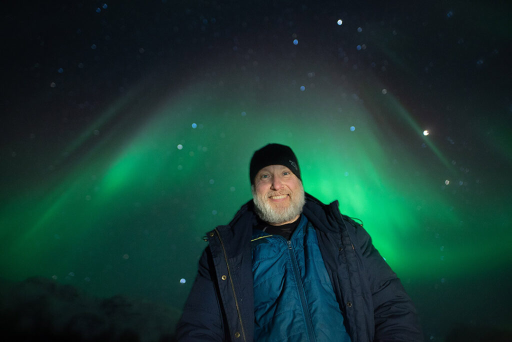 Homem feliz vendo a Aurora Boreal