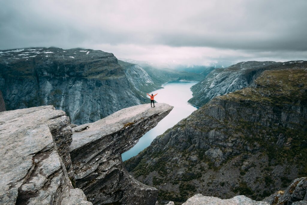 Pessoa comemora no topo da Trolltunga, na Noruega.