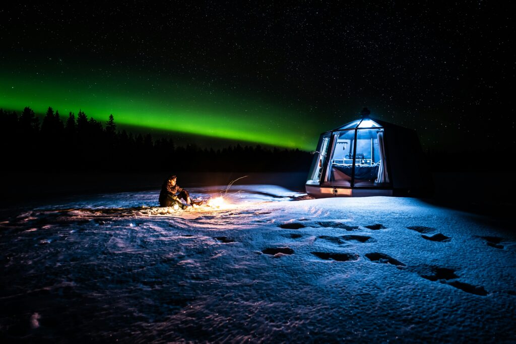 Iglu de Vidro com a Aurora Boreal iluminando o céu