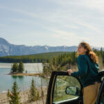 Woman looking at scenic lake in Banff during road trip with SUV in springtime