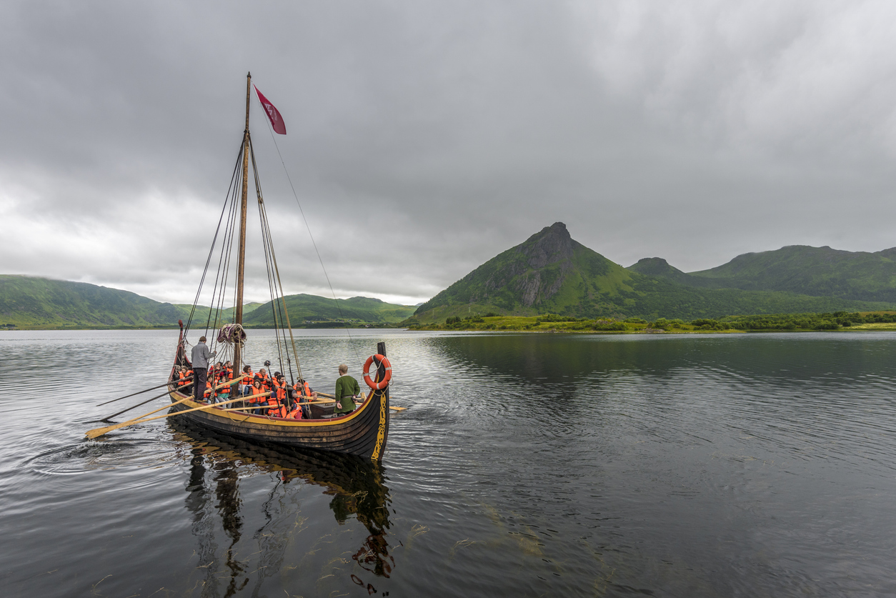 Departure of the Reconstructed Viking boat with tourists, in Innerpollen salty lake in Vestvagoy island of Lofoten archipelago. The area is a part of Lofotr Historical museum. Nordland, Northern Norway.