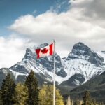 Bandeira do Canadá hasteada com montanhas ao fundo em Alberta