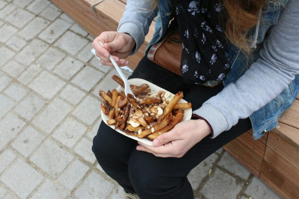 Mulher comendo poutine – Canadá
