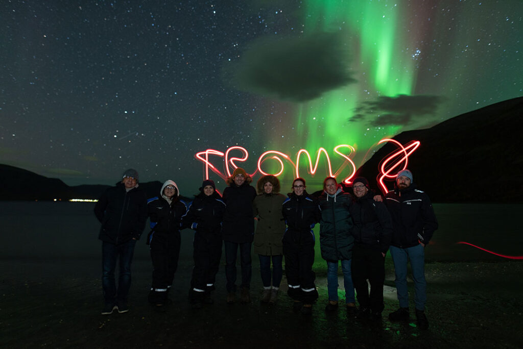 Grupo de pessoas diante da Aurora Boreal em Tromso, na Noruega