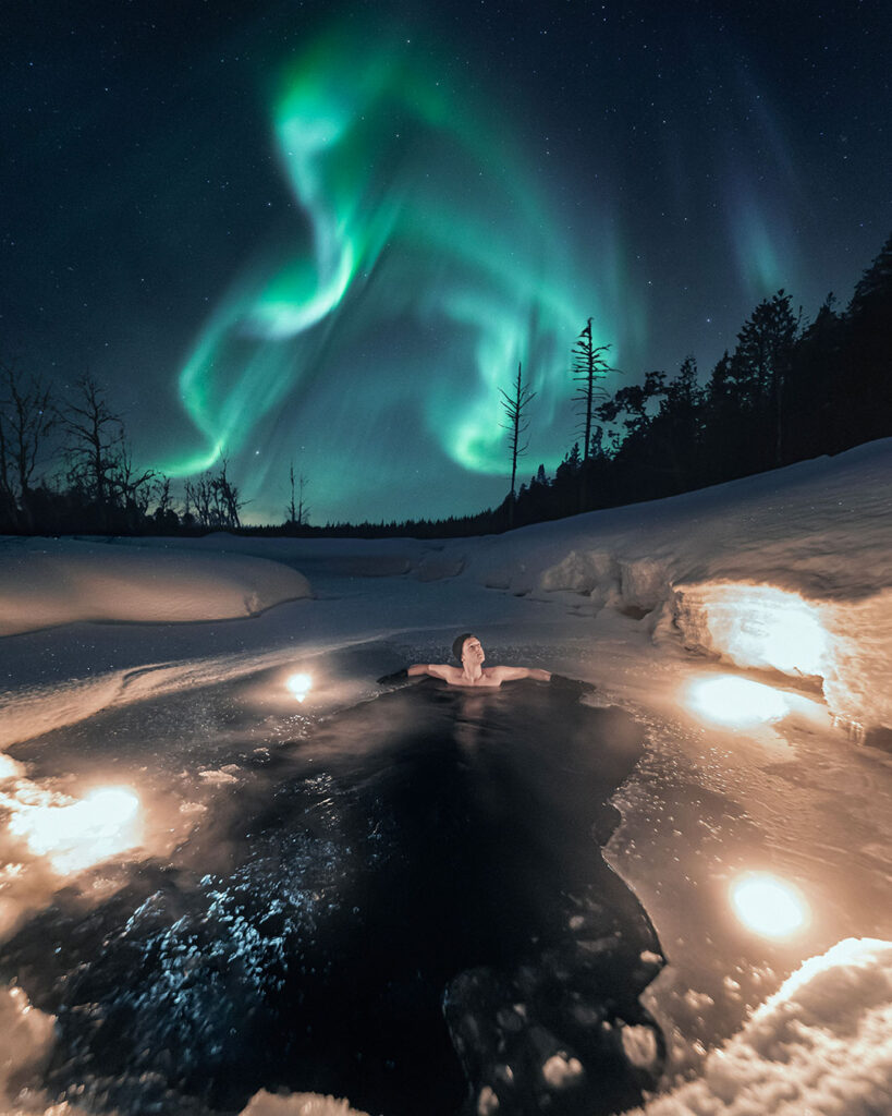Homem vendo a Aurora Boreal de dentro de uma sauda finlandesa